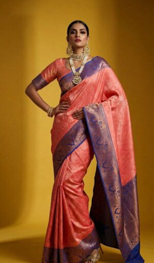 A striking coral peach Banarasi silk saree accented with royal blue zari weaving for a bold yet graceful look.